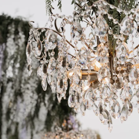 Close-up of the Philip crystal chandelier beneath greenery at an outdoor wedding in Greece