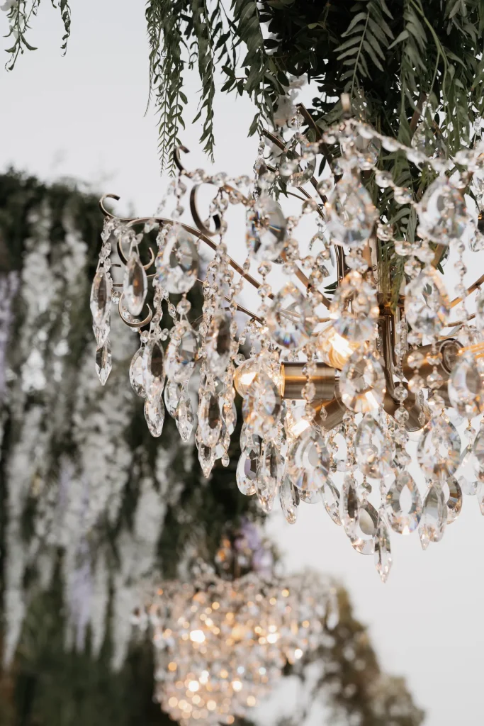 Close-up of the Philip crystal chandelier beneath greenery at an outdoor wedding in Greece